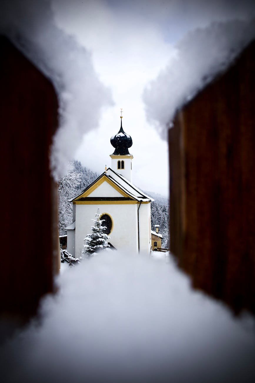 Snow-covered view of Kapelle Maria Rast in Thaur, Austria, framed by snow.